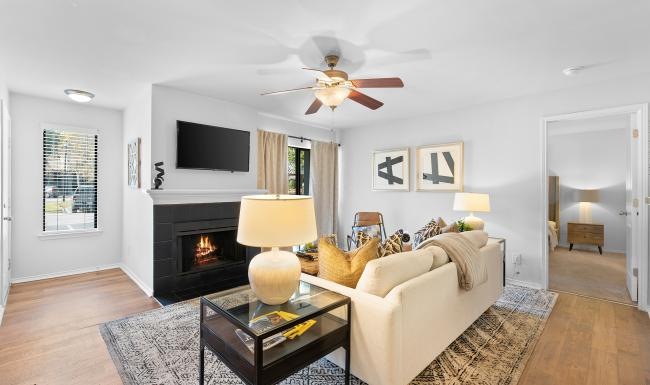 a living room with a fireplace tv and ceiling fan