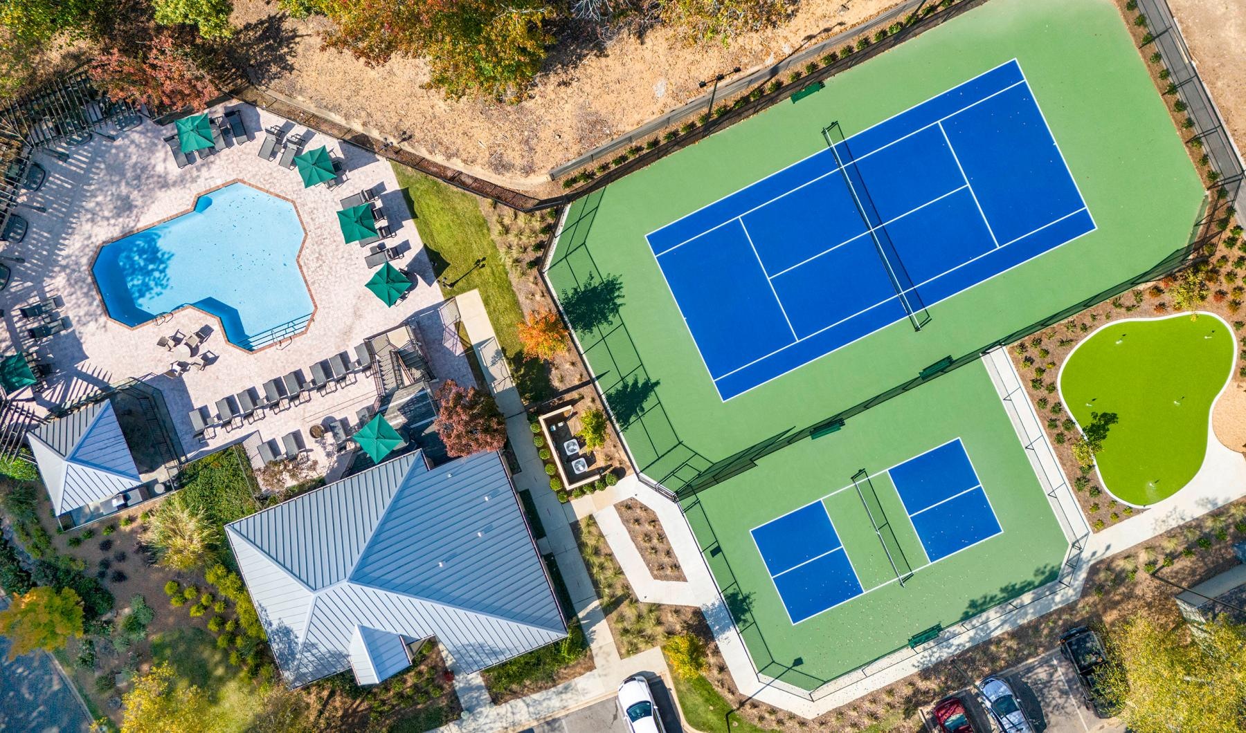 aerial view of a tennis court pickleball court putting green and clubhouse with pool