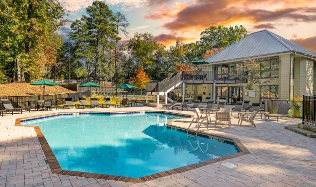 a swimming pool with trees and clubhouse behind it