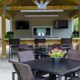 a patio with a table chairs and tvs
